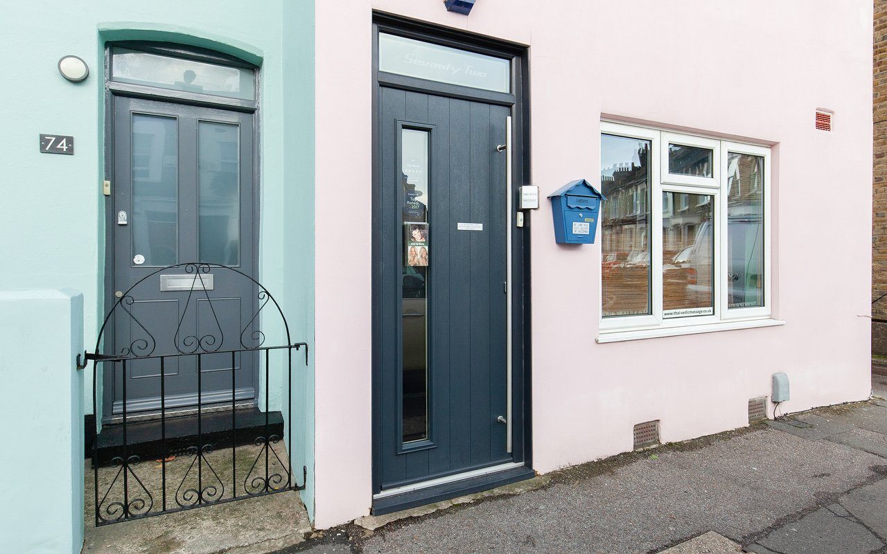 The pink and teal shopfront of Hair by Gerry's studio on Crawthew Grove, East Dulwich